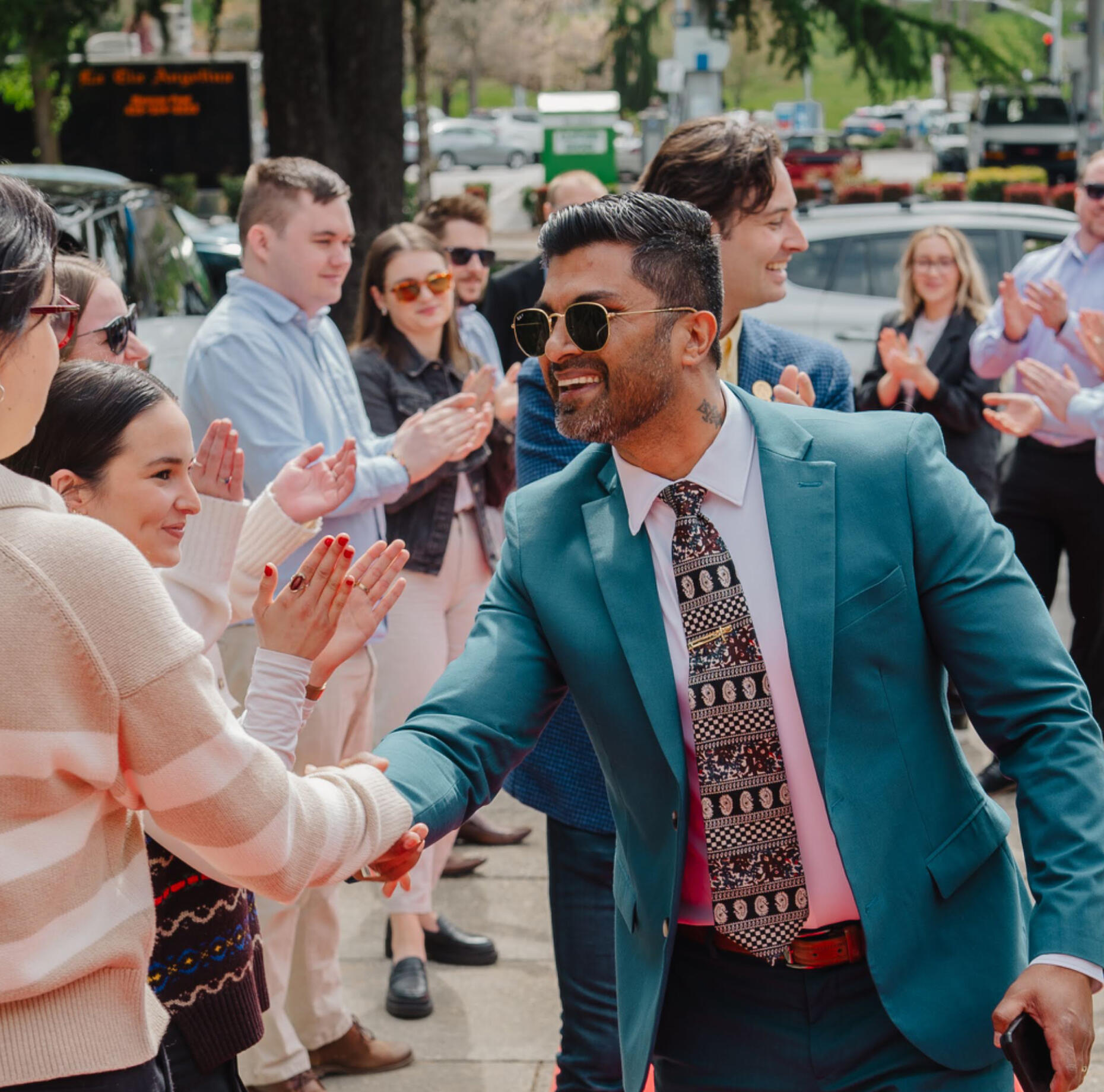Marshall Fernandez in a blue suit, professional insurance sales mentor shaking hands with other people while smiling.